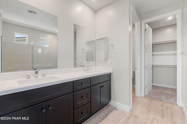 bathroom featuring vanity, wood-type flooring, and tiled shower