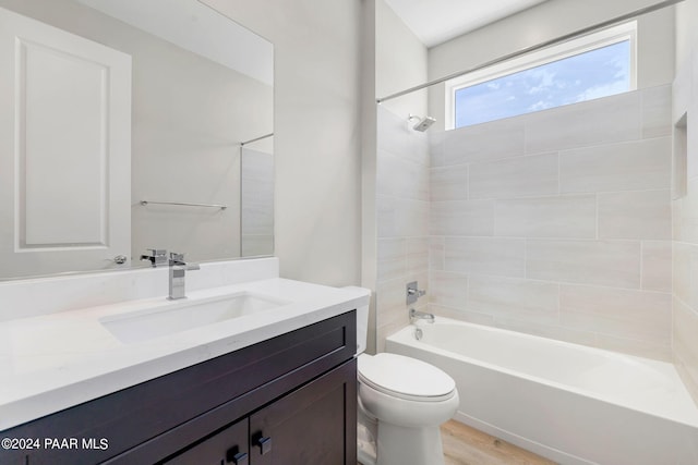 full bathroom featuring hardwood / wood-style floors, vanity, toilet, and tiled shower / bath combo