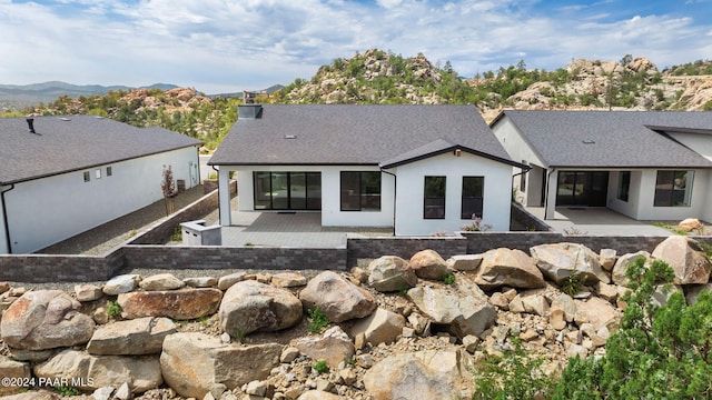 back of property featuring a mountain view and a patio