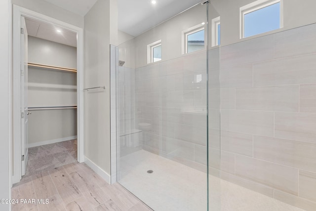 bathroom with tiled shower and wood-type flooring