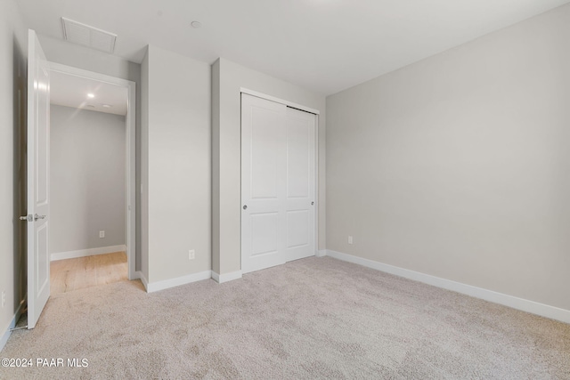 unfurnished bedroom featuring light colored carpet and a closet