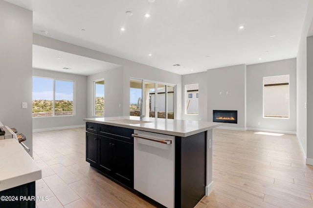 kitchen featuring stainless steel dishwasher, a kitchen island, sink, and light hardwood / wood-style flooring