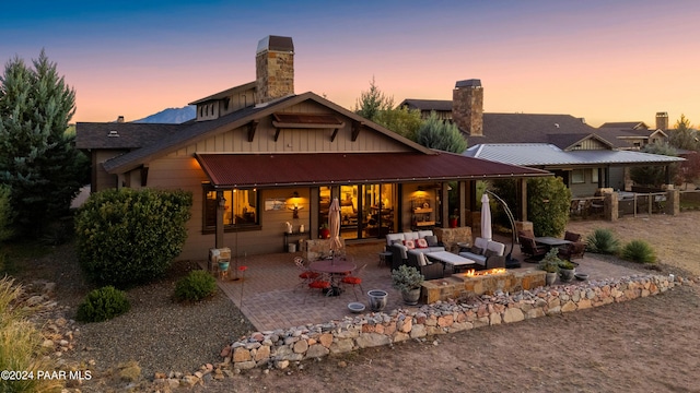 back house at dusk with a patio and an outdoor living space with a fire pit