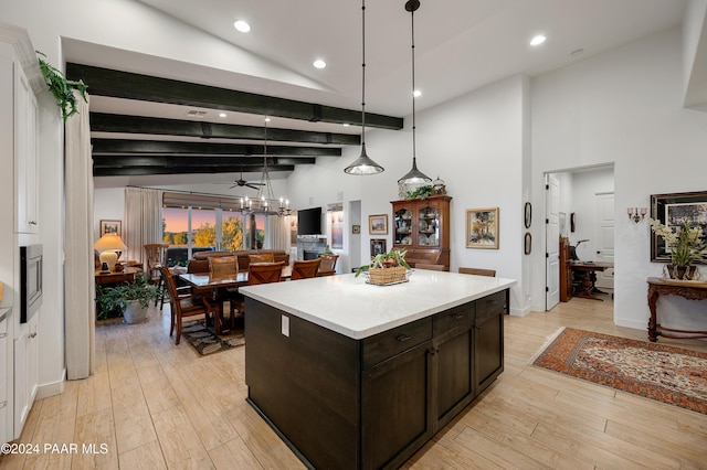 kitchen with dark brown cabinetry, stainless steel microwave, a center island, light hardwood / wood-style flooring, and decorative light fixtures