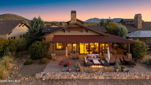 back house at dusk featuring a mountain view, a patio, and an outdoor living space with a fire pit