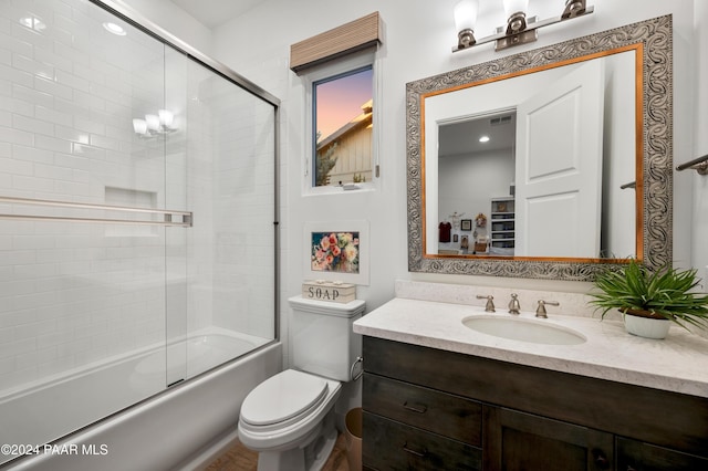 full bathroom featuring vanity, toilet, and shower / bath combination with glass door