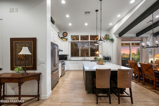 kitchen with a center island, stainless steel appliances, decorative light fixtures, white cabinets, and light wood-type flooring