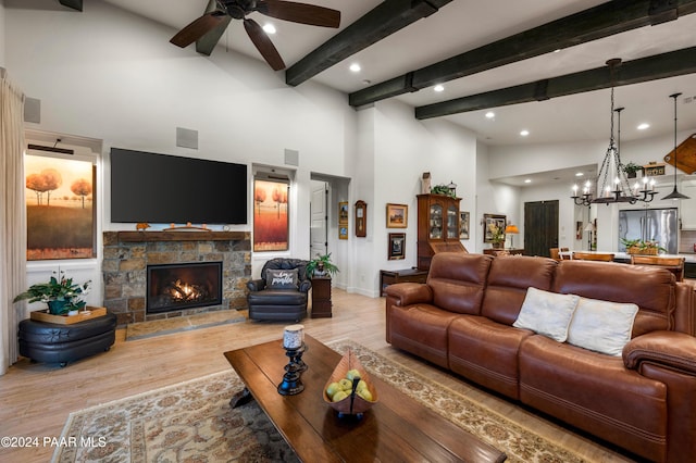 living room with beam ceiling, a fireplace, a high ceiling, and light hardwood / wood-style flooring