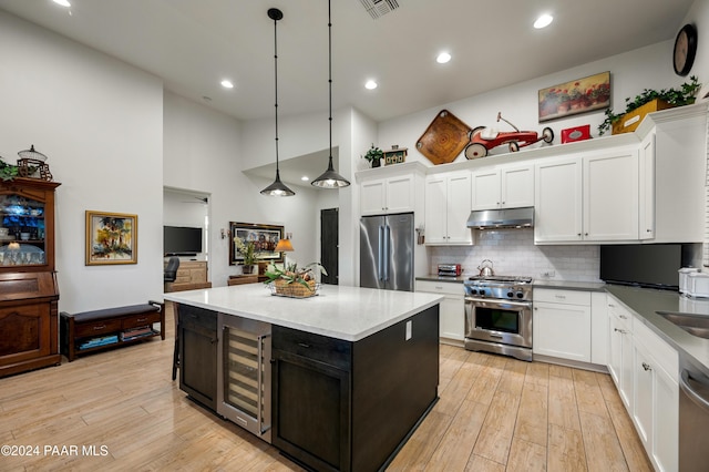 kitchen featuring hanging light fixtures, stainless steel appliances, wine cooler, white cabinets, and light wood-type flooring