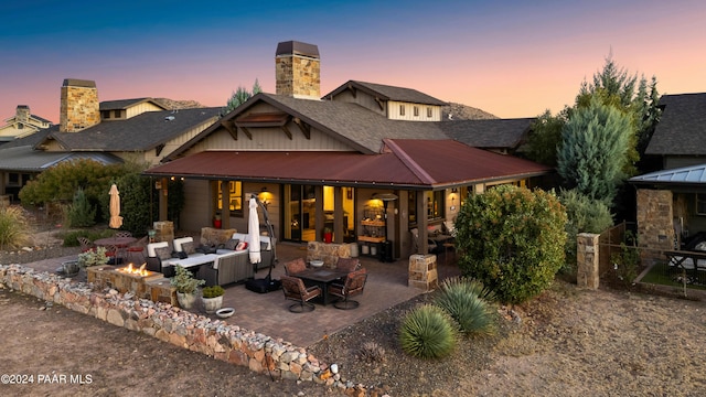 back house at dusk featuring a patio area and an outdoor living space with a fire pit