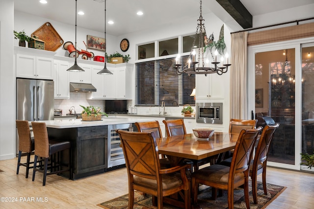 dining room with sink, beverage cooler, a notable chandelier, and light wood-type flooring