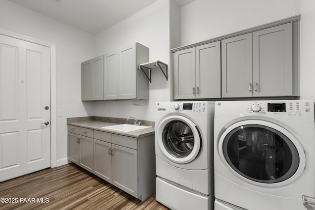 washroom featuring sink, dark hardwood / wood-style floors, cabinets, and separate washer and dryer