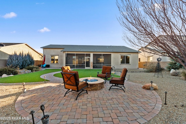 back of property with a sunroom, a fire pit, and a patio