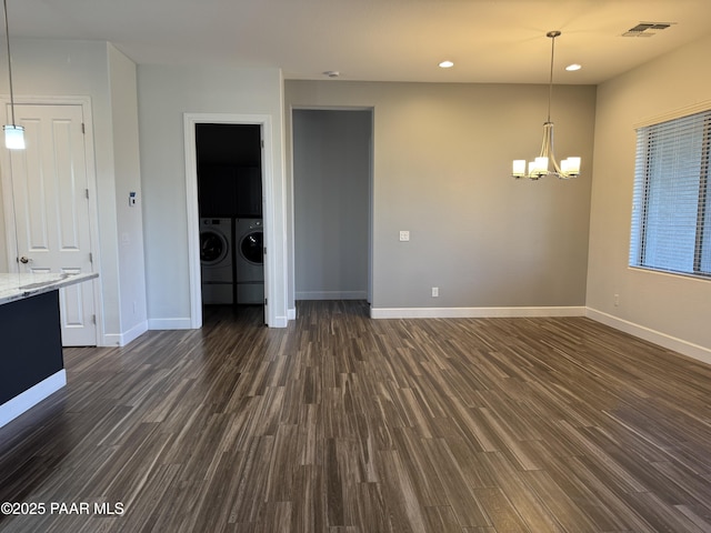 unfurnished living room featuring washing machine and clothes dryer, dark wood-type flooring, visible vents, and an inviting chandelier