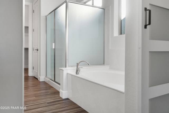 bathroom featuring plus walk in shower and hardwood / wood-style flooring