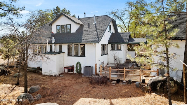 rear view of house featuring roof with shingles, central AC, and stucco siding