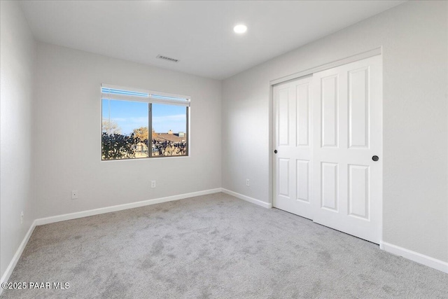 unfurnished bedroom featuring light carpet and a closet