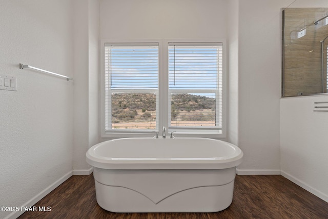 full bath with wood finished floors, baseboards, a freestanding bath, and tiled shower