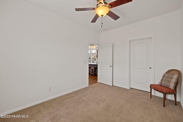 sitting room featuring ceiling fan, baseboards, and light carpet