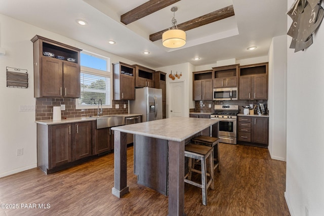 kitchen with appliances with stainless steel finishes, open shelves, a sink, and a breakfast bar