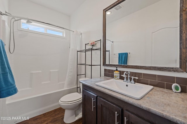 bathroom with tasteful backsplash, toilet, shower / tub combo, wood finished floors, and vanity