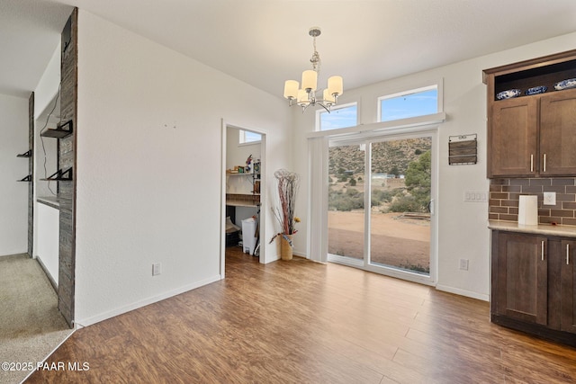 unfurnished dining area with baseboards, wood finished floors, and a chandelier