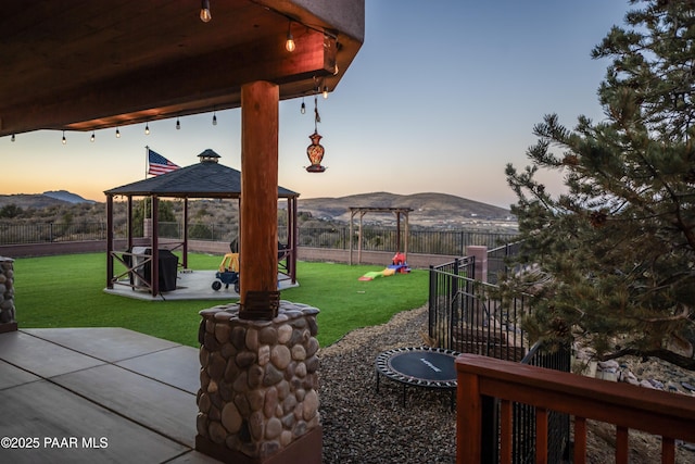 yard at dusk with a mountain view, a gazebo, and a patio