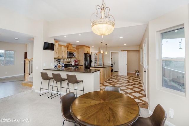 kitchen with sink, light brown cabinets, appliances with stainless steel finishes, kitchen peninsula, and pendant lighting