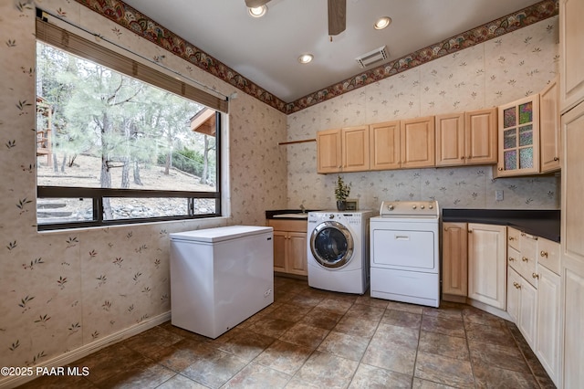 clothes washing area with visible vents, cabinet space, wallpapered walls, and separate washer and dryer