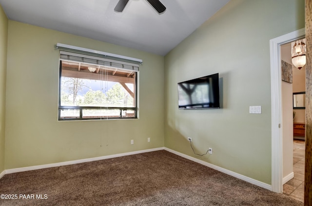 carpeted spare room featuring baseboards, ceiling fan, and vaulted ceiling