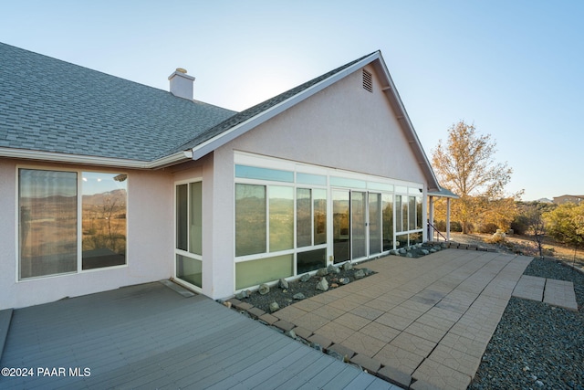 rear view of property featuring a wooden deck and a sunroom