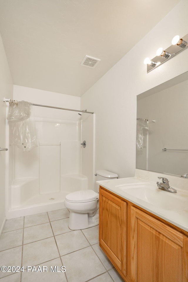 bathroom with tile patterned flooring, vanity, toilet, and walk in shower