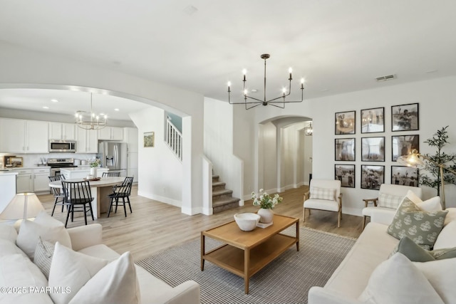 living room with an inviting chandelier and light wood-type flooring