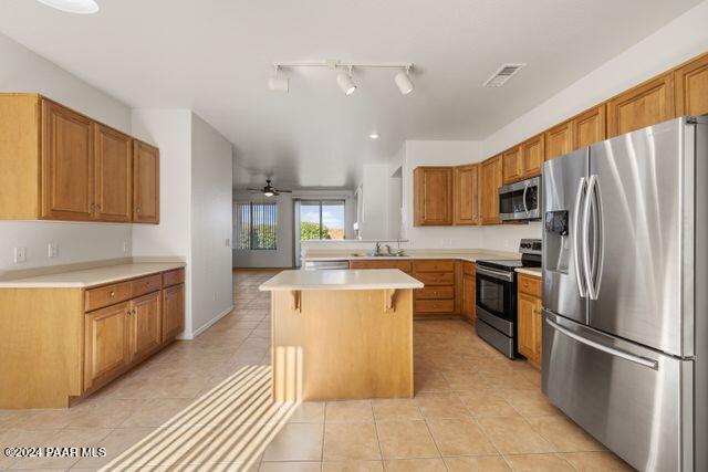 kitchen featuring ceiling fan, a center island, a breakfast bar, light tile patterned flooring, and appliances with stainless steel finishes