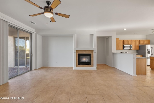 unfurnished living room with a fireplace, ceiling fan, and light tile patterned flooring