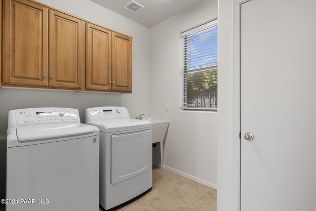 washroom featuring cabinets, light tile patterned flooring, and washing machine and clothes dryer