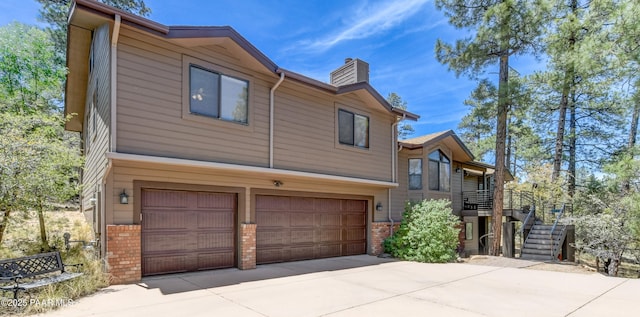 1585 Range Rd, Prescott, AZ 86303 - view of side of property with a garage, a chimney, brick siding, concrete driveway, and stairs