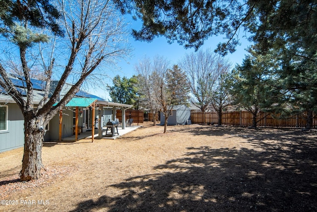 view of yard featuring a patio, a storage unit, an outbuilding, and a fenced backyard