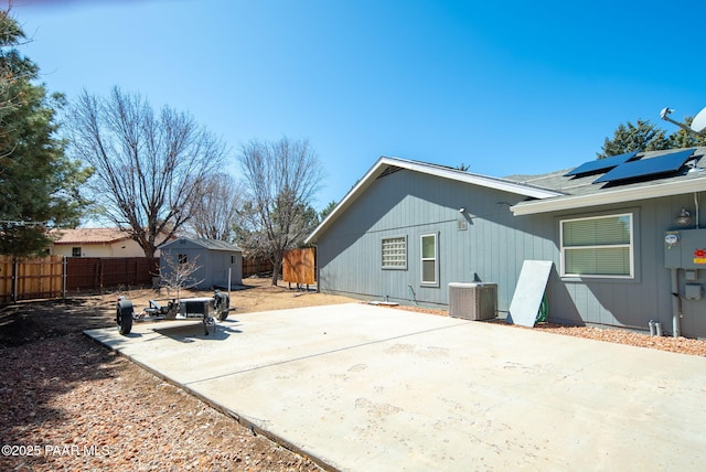 exterior space with a patio area, central AC unit, a storage shed, a fenced backyard, and an outbuilding