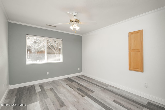 spare room with visible vents, baseboards, wood finished floors, and crown molding