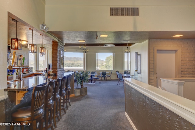 interior space featuring an inviting chandelier, a mountain view, visible vents, and dark colored carpet