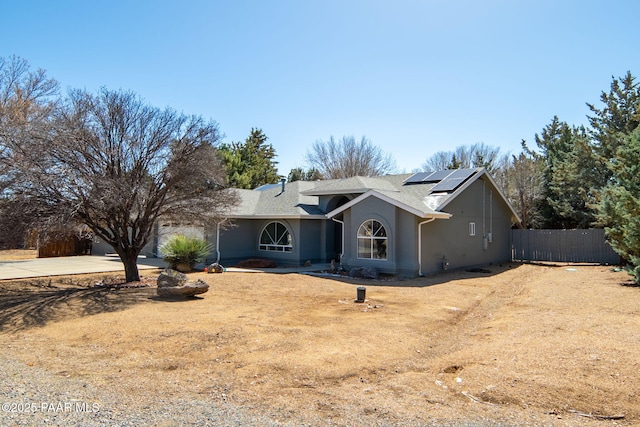 single story home featuring stucco siding, fence, concrete driveway, an attached garage, and solar panels