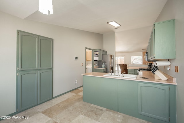 kitchen featuring green cabinets, a peninsula, vaulted ceiling, and stainless steel appliances