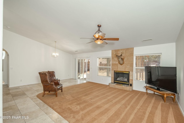 living area with visible vents, lofted ceiling, a tile fireplace, light tile patterned flooring, and arched walkways