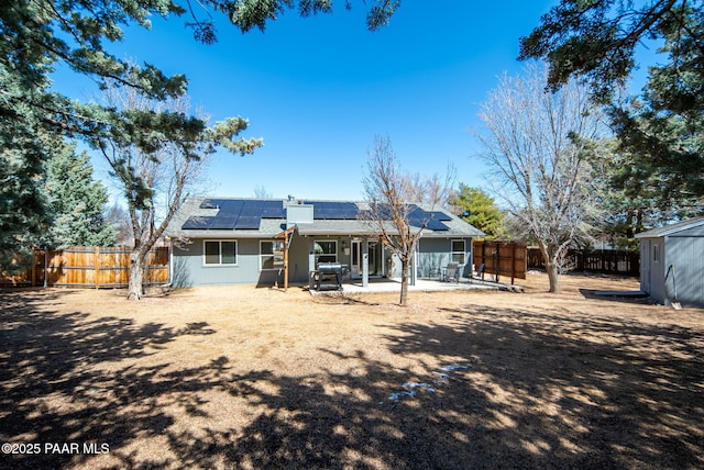 rear view of house featuring a storage unit, roof mounted solar panels, an outdoor structure, and a patio area