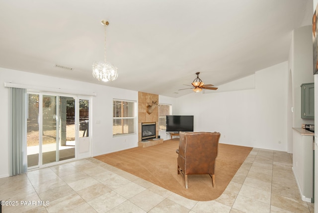 living area with visible vents, a tile fireplace, ceiling fan with notable chandelier, light colored carpet, and vaulted ceiling