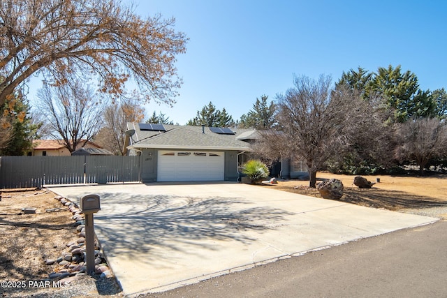 single story home with solar panels, driveway, an attached garage, and fence