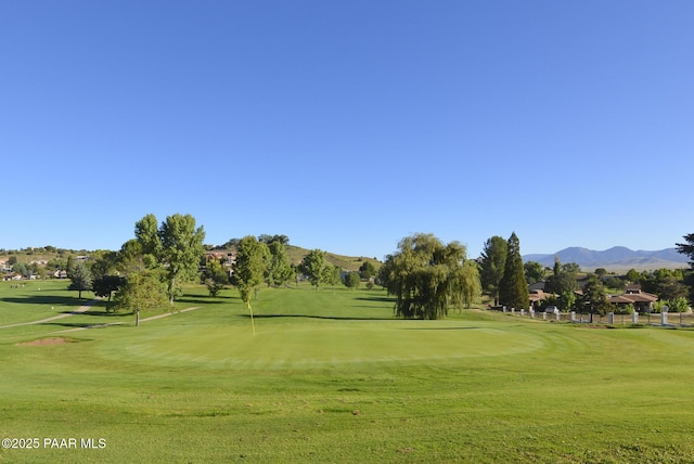 view of community featuring a lawn, a mountain view, and view of golf course