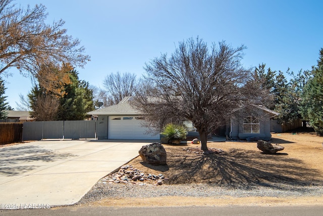 obstructed view of property featuring concrete driveway, an attached garage, and fence