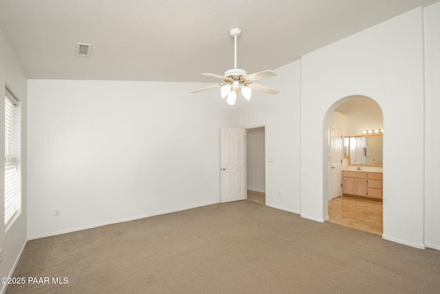 unfurnished bedroom featuring visible vents, high vaulted ceiling, ensuite bathroom, carpet floors, and arched walkways